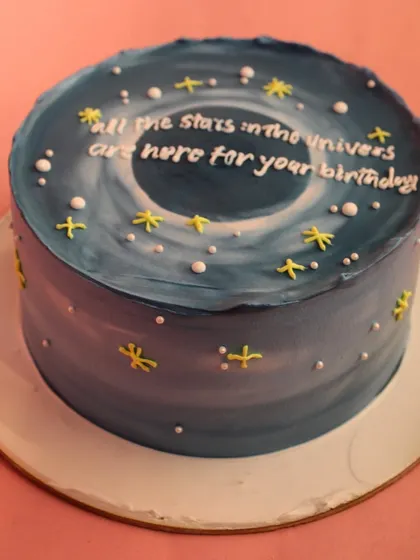 A cake for the stargazer. This galaxy-themed cake features a deep blue cosmic swirl, stars, and a sweet message, perfect for someone who is your universe.