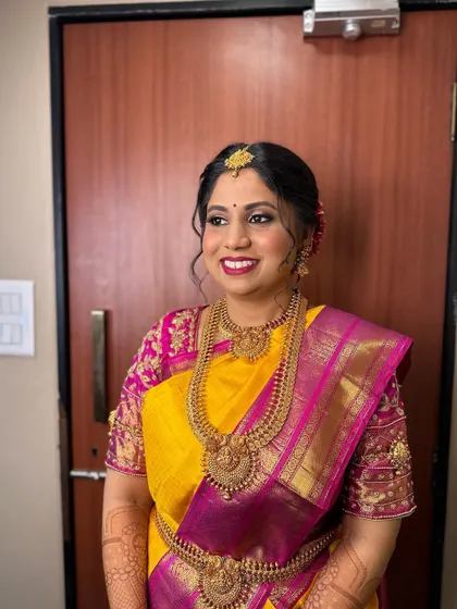 A classic South Indian bridal look with a neat updo and traditional jewellery. This hairstyle is perfect for a bride wearing a vibrant silk saree.