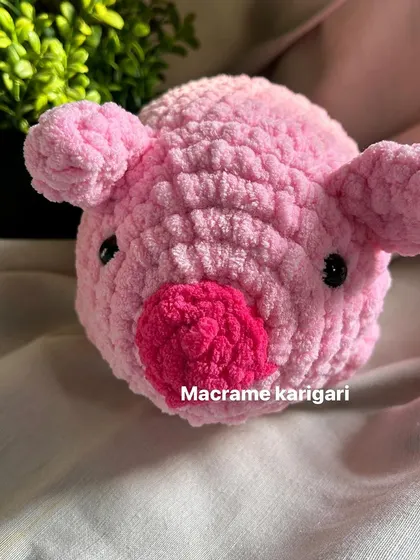 A front view of our crochet pig toy. Its simple, round shape and bright pink color make it an adorable addition to any toy collection or as a piece of farm-themed decor.