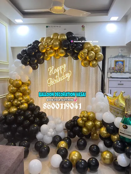 A classic half-arch balloon decoration for a birthday party. The black, gold, and white color scheme is timeless, and the setup includes fun elements like a champagne bottle balloon.