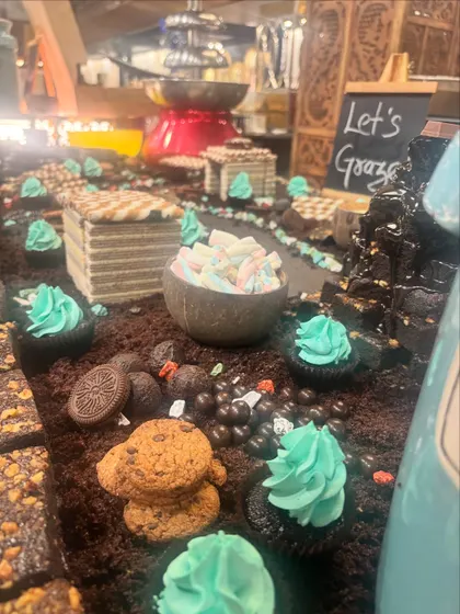 This angle highlights the details of the chocolate grazing table, including the central chocolate fountain, individual cupcakes with mint frosting, and a variety of cookies and chocolate balls ready for guests.