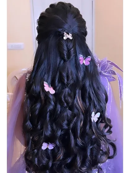 A whimsical half-updo with a hidden braid and cascading curls, decorated with colorful butterfly clips for a playful and unique party look.