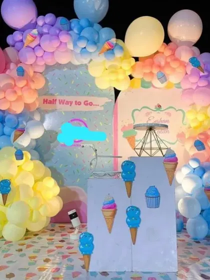 A sweet ice cream-themed party decoration. The setup is filled with pastel-colored balloons resembling scoops of ice cream, themed cutouts, and a "Half Way to Go" sign.