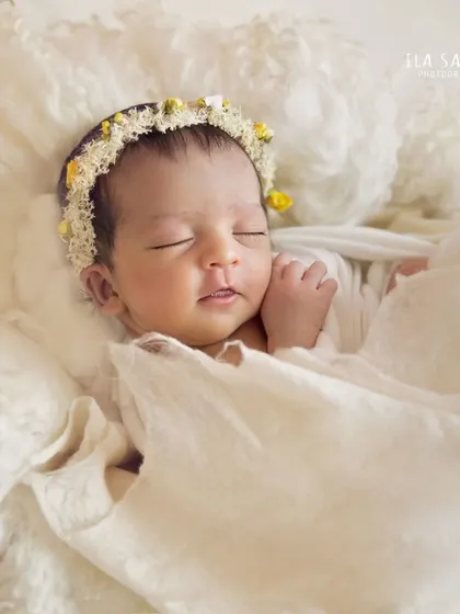 This close-up of a sleeping newborn shows off her delicate features. The simple white wrap and tiny yellow flower crown add just a touch of color and softness.