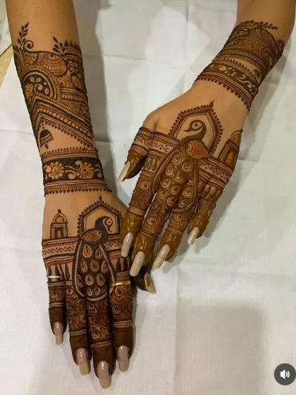 This design combines architectural elements with graceful peacocks on the palms and fingers, extending into a full arm design.