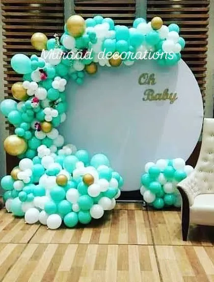 This 'Oh Baby' setup uses a refreshing color palette of teal, white, and gold. The design includes a circular backdrop, 'BABY' blocks, and a comfortable chair for the mom-to-be, making it a perfect photo corner.