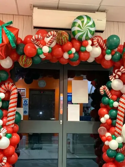 I create bold and festive entrances to welcome customers during the holidays. This Christmas balloon arch is packed with red, green, and white balloons, candy canes, and gift box accents.