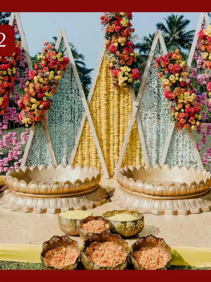 A unique Haldi ceremony setup with triangular backdrops and large brass urlis for the rituals. The geometric design combined with traditional elements gives it a modern yet classic feel.