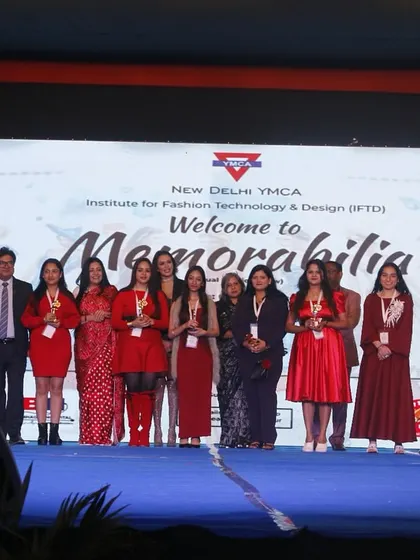 A group of student designers in red outfits stands with the jury after receiving their awards.