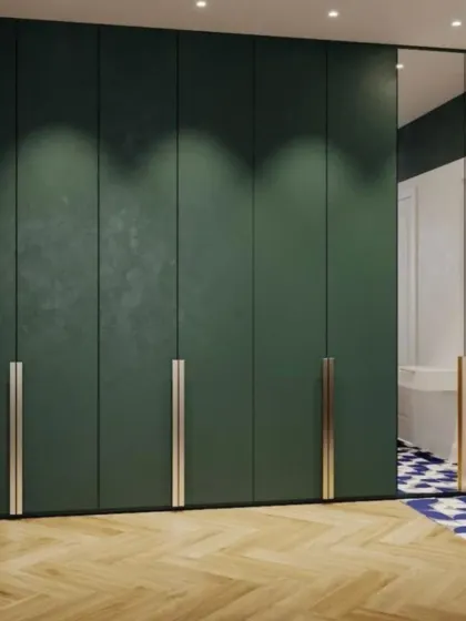 A bold, forest green wardrobe with long, elegant brass handles makes a powerful style statement. The design includes a full-length mirror panel, adding functionality and making the room feel larger.