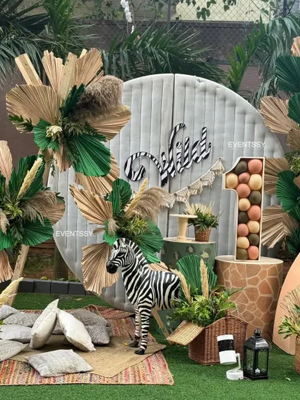 A "Wild One" first birthday with a boho-jungle aesthetic. This setup uses natural textures like dried palm leaves, pampas grass, and wood, along with animal props, to create a stylish and adventurous atmosphere.