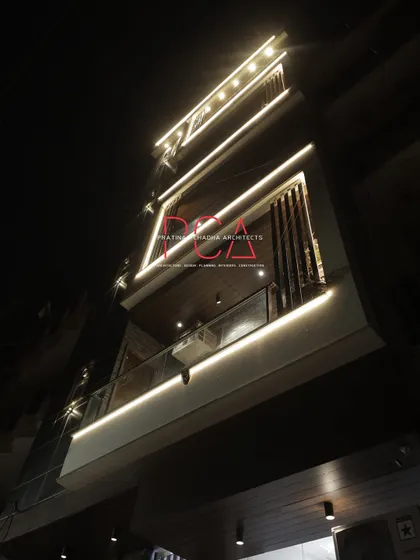 A close-up, low-angle night view of the upper balconies of The Cursive Abode, highlighting the detail in the lighting design.