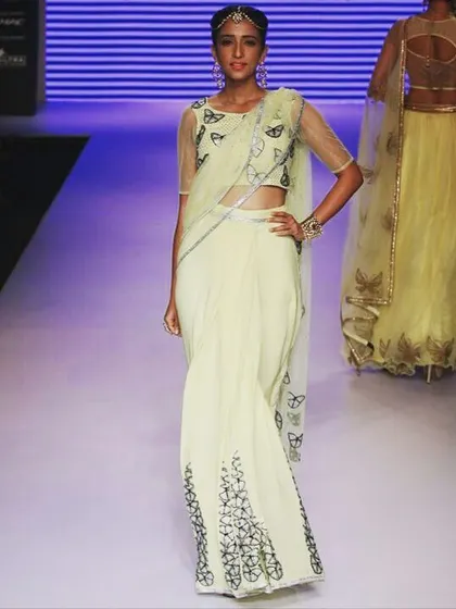 A moment from the runway featuring a lime yellow georgette saree. The design is elevated with delicate butterfly motifs and Swarovski crystal detailing, blending modern style with classic elegance for a high-fashion statement.