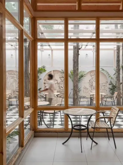 A small, intimate seating area looks out into the main courtyard. The use of extensive glazing dissolves the boundary between the indoor and outdoor dining spaces.