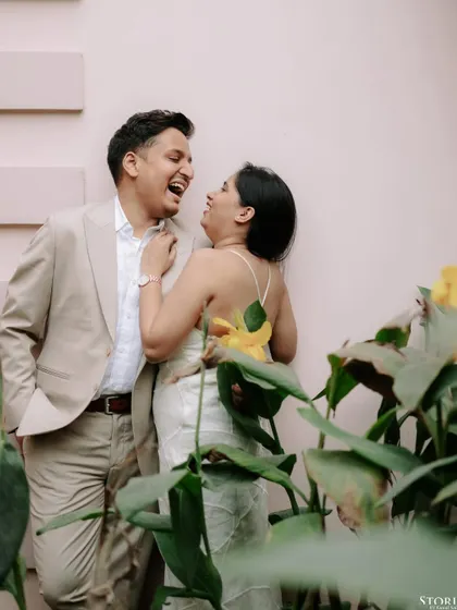 Another joyful, laughing portrait of the couple against a pink wall, capturing their playful chemistry.