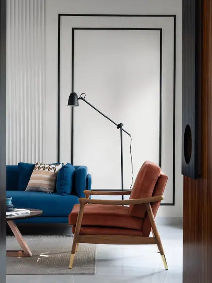 A peek into the living room from the doorway, framing the terracotta armchair and the modern floor lamp, hinting at the colorful and contemporary space within.