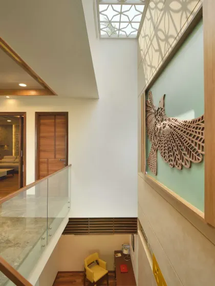 The third-floor lobby of Kavyam Residence features a double-height volume illuminated by a patterned skylight. This not only brings in light but also casts dynamic shadows, with a sculptural bird artwork anchoring the vertical wall.