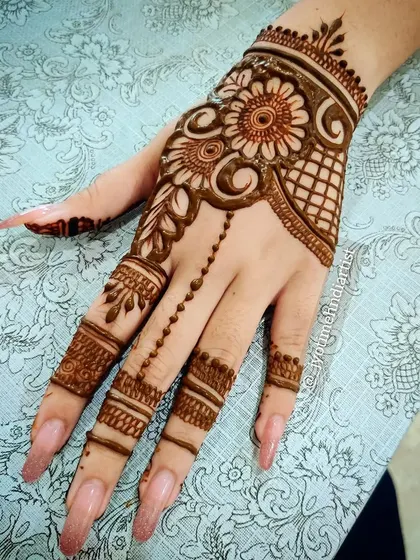 A chic and modern design featuring a floral vine connected to the fingers with a delicate chain of dots. This is a popular choice for parties and engagements.