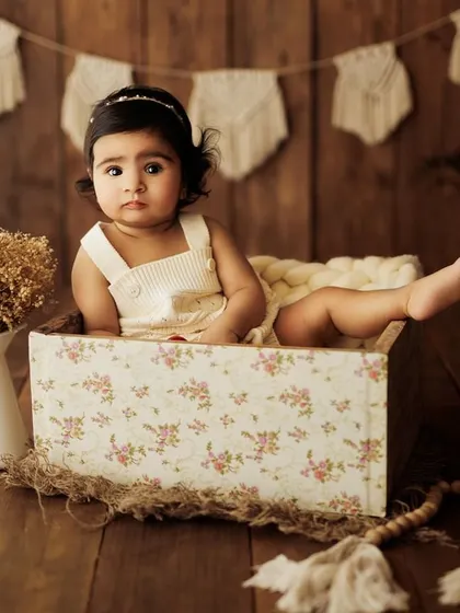 A quiet moment of observation from a baby girl in a floral box. These sessions capture all facets of a baby's personality, from playful to thoughtful.
