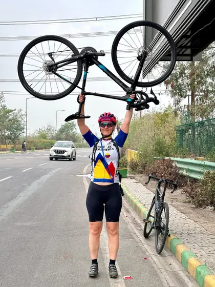A triumphant pose, lifting her bike overhead after a challenging ride.