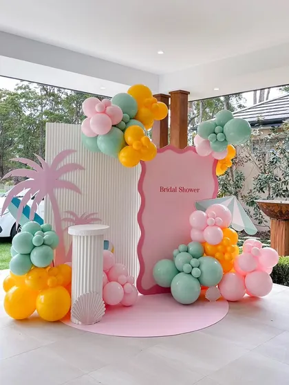 I can create a fun, tropical-themed bridal shower for an outdoor setting. This setup uses playful colors, a palm tree cutout, and balloon arrangements to bring a beachy, vacation vibe to the party.
