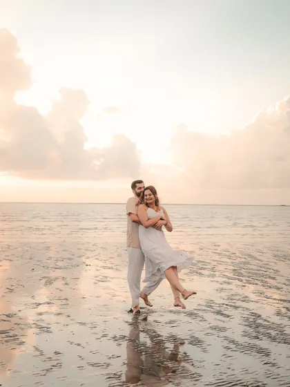 A playful and joyous moment on a Goan beach, with the groom lifting the bride as the waves reflect the soft sky. This captures the fun, relaxed vibe of a coastal pre-wedding shoot.