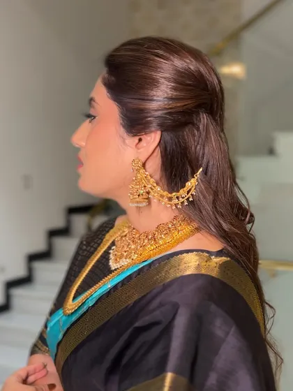 A complete look that is both timeless and modern. The dark saree paired with gold jewelry and a simple hairstyle is a testament to understated elegance.