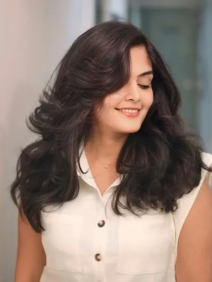 Vibrant hues, bold views. This look features a deep, rich brown color styled with voluminous, bouncy layers.