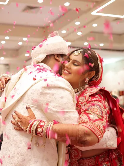 A purely candid moment of joy as the bride hugs the groom, showered in a rain of pink flower petals. These are the unscripted, emotional memories I aim to preserve.