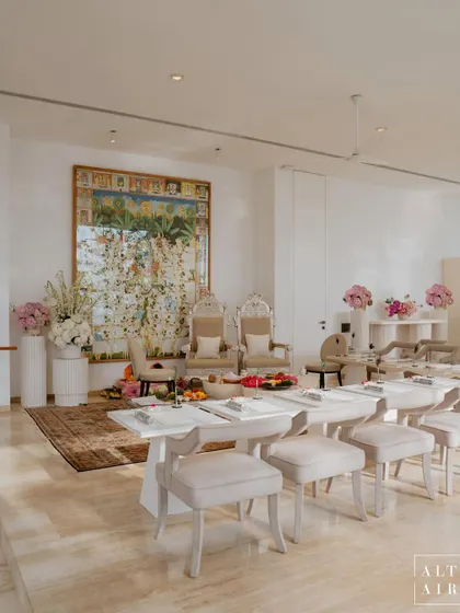 The indoor setup for the Lagan Lakhwanu ceremony. The design was modern, minimal, and spiritual, with elegant white furniture, traditional silver chairs, and a beautiful Pichwai painting as the backdrop.