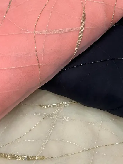 This embroidered organza with delicate beadwork is available in multiple colors, including peach, navy, and off-white, offering versatile options for elegant outfits.