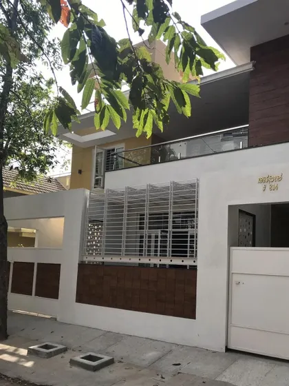 The entrance view of the 'Avaneesha' residence, featuring a clean, minimalist boundary wall with brick and white plaster that complements the main structure.