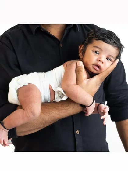 A father's strong arm is the safest place for his son. This pose beautifully showcases how tiny and new the baby is, held securely by his dad.