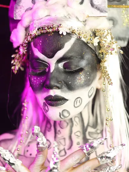 A close-up on the face, showing the detailed nail art and the contrast between the black and white makeup.