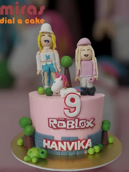 A fun and girly Roblox-themed cake. This pink cake features custom avatars, a unicorn, and the Roblox logo, perfect for a gamer girl's ninth birthday celebration.
