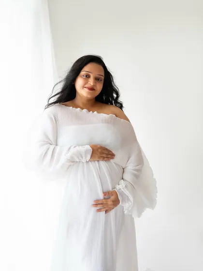 A beautiful, happy portrait of the mom-to-be looking directly at the camera with a warm smile. The flowing white gown and natural light give her an amazing glow.