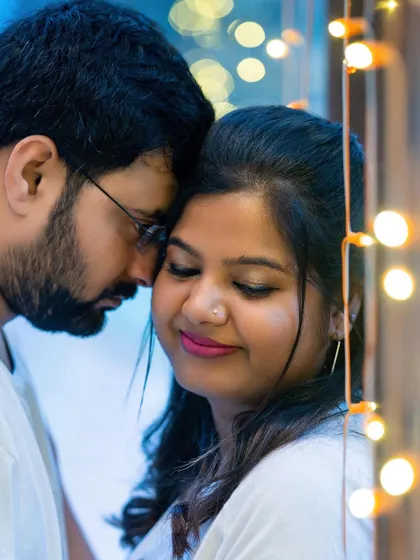 A close-up, intimate portrait of a couple, with the warm glow of fairy lights creating a romantic bokeh effect.