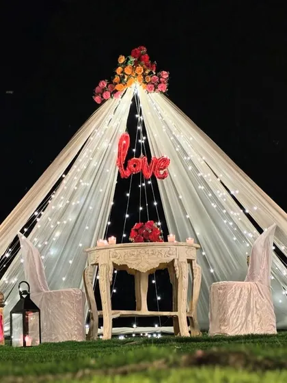 A beautiful view of the romantic tent proposal setup, illuminated by fairy lights against the night sky.