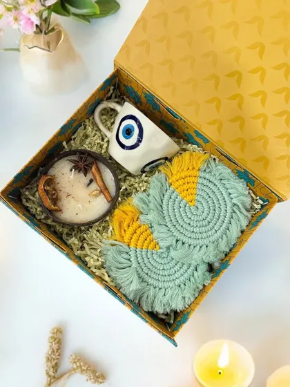 An overhead shot of the evil eye themed hamper, highlighting the vibrant, handcrafted macrame coasters and the natural aesthetic of the coconut shell candle.