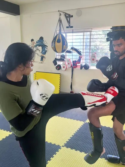 A student lands a clean high kick during a kickboxing sparring session. This is the result of consistent practice and drilling.