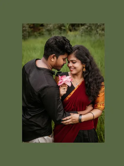 An intimate close-up of a couple in a field, the groom-to-be whispering to his partner who holds a lotus flower.