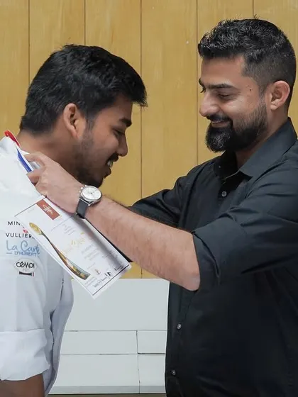 Chef Avin, the mentor for our Mondial Du Pain team, places a medal on his student. The bond between our mentors and students is at the heart of our academy's success.