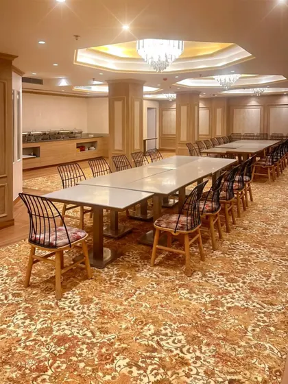 A site meeting in the nearly completed Bhopal banquet hall. This shows the space configured for a large dinner, highlighting the custom carpet and elegant wall paneling.
