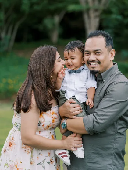 A family laughing together in a field of tall grass. This is the result of letting go and just having fun during the session.