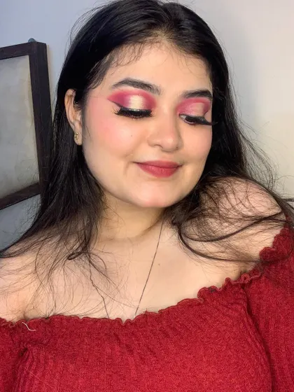 A close-up of a dramatic red-pink cut crease eye makeup look.