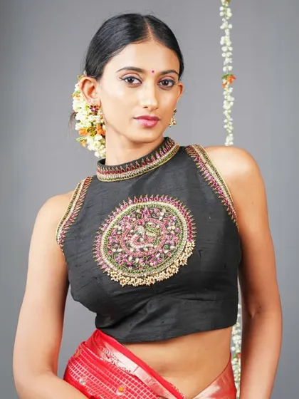A stunning hand-embroidered sleeveless blouse with a central peacock motif. This is a piece of wearable art, perfect for making a statement at any festive occasion.