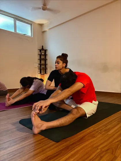 Offering a gentle adjustment in Paschimottanasana (Seated Forward Fold). This helps the student to fold from the hips and protect his lower back.