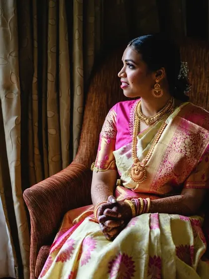 A quiet moment of reflection for the bride, Amrutha. Seated by the window, the natural light beautifully illuminates her, creating a soft and elegant bridal portrait.