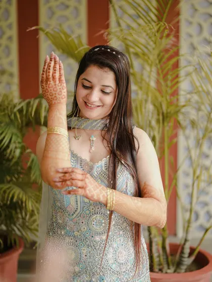 A beautiful portrait of the bride admiring her Mehendi design. The soft lighting and her gentle smile highlight her happiness and anticipation.