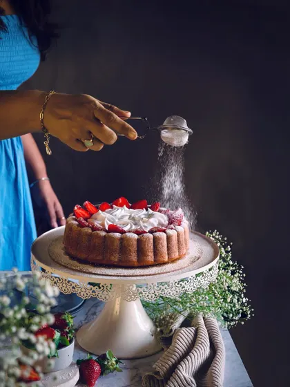 I love working with fresh, seasonal ingredients. Here, I am putting the finishing touch on a beautiful strawberry cake, made with a Nordic Ware pan to give it a distinctive shape and topped with fresh cream and berries.
